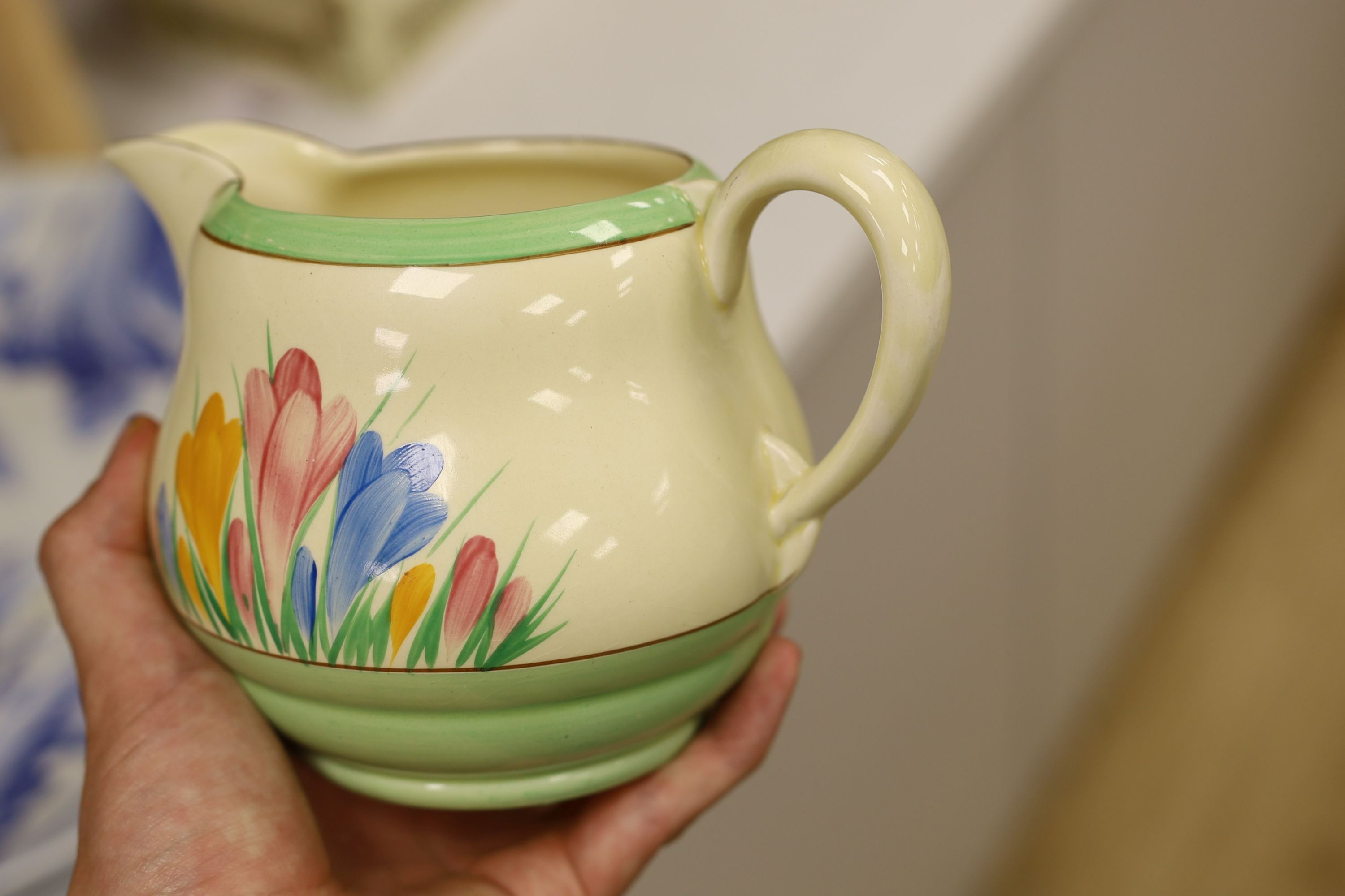 A Clarice Cliff crocus design milk jug and a Bizarre patterned side plate, jug 11.5 cms high